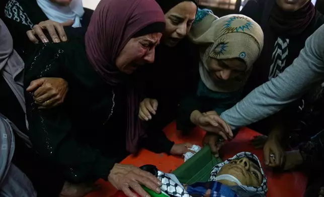 Wafa Hammad, 52, left, mother of Palestinian teen Yamen Hamed, 15 who was allegedly killed by the Israeli army during overnight clashes, cries while she takes the last look at his body during his funeral in the West Bank town of Silwad Friday, Oct. 31, 2025. (AP Photo/Nasser Nasser)