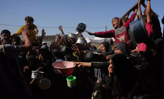 Palestinians wait to get donated sugar and rice at a community kitchen in Khan Younis, southern Gaza Strip, Friday, Oct. 31, 2025. (AP Photo/Abdel Kareem Hana)