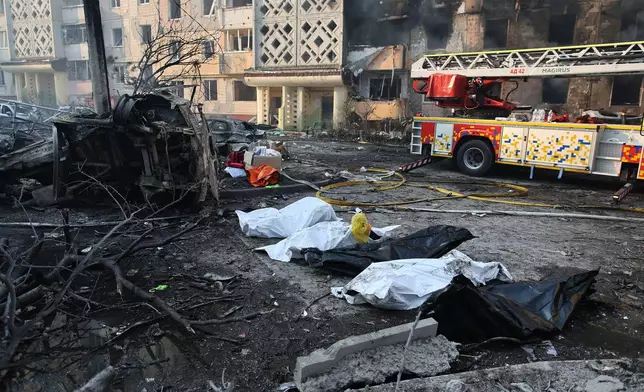 Dead bodies in plastic bags lie on the ground in front of residential building which was heavily damaged after a Russian strike on Ternopil, Ukraine, on Wednesday, Nov. 19, 2025. (AP Photo/Vlad Kravchuk)
