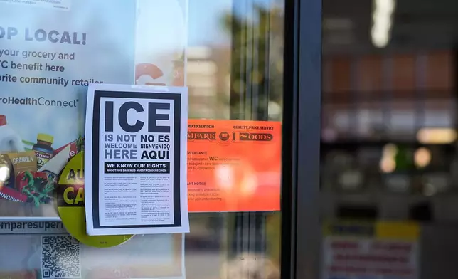 A sign reading 'ICE is not welcome here' is displayed outside of store front amidst federal law enforcement presence, Monday, Nov. 17, 2025, in Charlotte, N.C. (AP Photo/Matt Kelley)