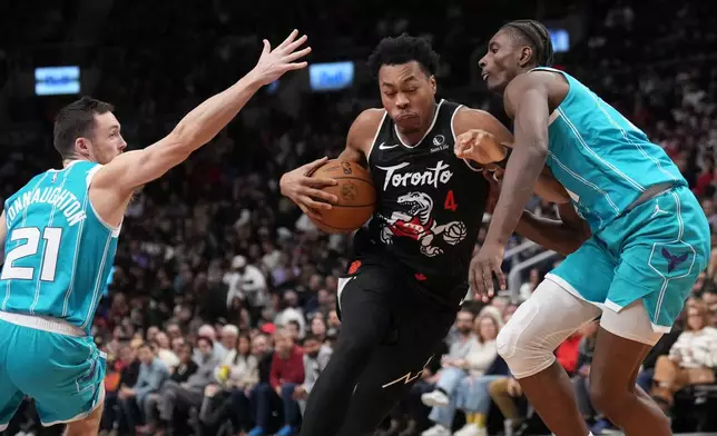Toronto Raptors forward/guard Scottie Barnes (4) drives past Charlotte Hornets forward Moussa Diabaté, right, and guard Pat Connaughton (21) during second-half NBA basketball game action in Toronto, Monday, Nov. 17, 2025. (Nathan Denette/The Canadian Press via AP)
