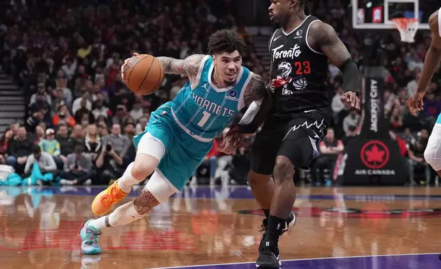 Charlotte Hornets guard Lamelo Ball (1) drives around Toronto Raptors guard Jamal Shead (23) during the first half of an NBA basketball game in Toronto on Monday, Nov. 17, 2025. (Nathan Denette/The Canadian Press via AP)