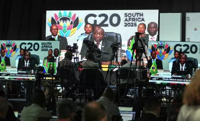 Members of the media watch on screens as South African President Cyril Ramaphosa addresses the opening session of the G20 leaders' summit, in Johannesburg, South Africa, Saturday, Nov. 22, 2025. (AP Photo/Jerome Delay)