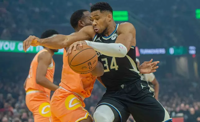 Milwaukee Bucks' Giannis Antetokounmpo (34) drives to the basket as Cleveland Cavaliers' Evan Mobley, second from right, defends during the first half of an NBA basketball game in Cleveland, Monday, Nov. 17, 2025. (AP Photo/Phil Long)