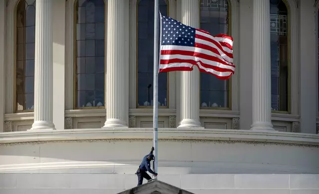 A worker lowers an American flag to half-staff, Tuesday, Nov. 4, 2025, at the Capitol in Washington. (AP Photo/Mark Schiefelbein)