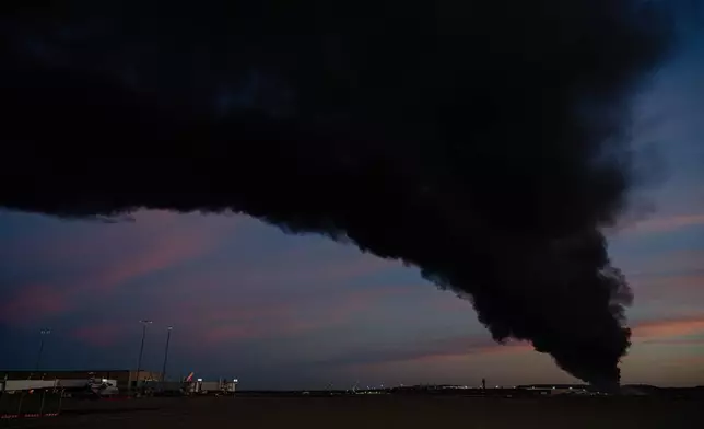 A plume of smoke wafts over airport property after reports of a plane crash at Louisville International Airport, Tuesday, Nov. 4, 2025, in Louisville, Ky. (AP Photo/Jon Cherry)