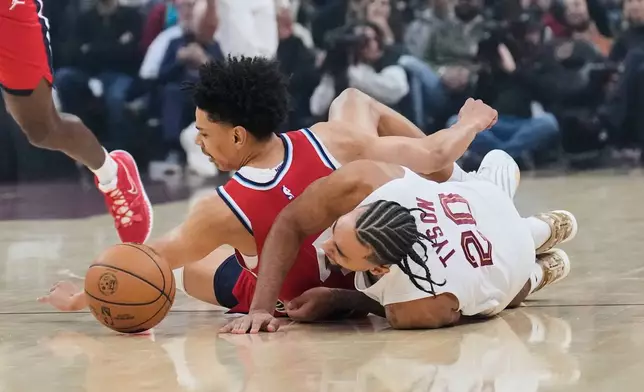Los Angeles Clippers guard Kobe Sanders, left, and Cleveland Cavaliers guard Jaylon Tyson (20) reach for the ball in the first half of an NBA basketball game Sunday, Nov. 23, 2025, in Cleveland. (AP Photo/Sue Ogrocki)