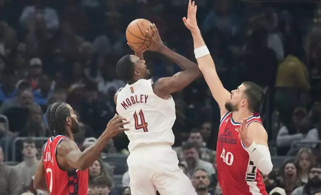 Cleveland Cavaliers center Evan Mobley (4) shoots between Los Angeles Clippers forward Kawhi Leonard, left, and center Ivica Zubac (40) in the first half of an NBA basketball game Sunday, Nov. 23, 2025, in Cleveland. (AP Photo/Sue Ogrocki)