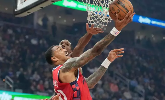 Los Angeles Clippers forward John Collins, front, shoots in front of Cleveland Cavaliers center Evan Mobley, rear, in the first half of an NBA basketball game Sunday, Nov. 23, 2025, in Cleveland. (AP Photo/Sue Ogrocki)