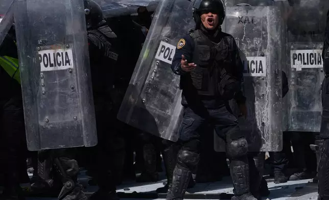 An officer yells at protesters charging at police during a youth anti-government march in Mexico City, Saturday, Nov. 15, 2025. (AP Photo/Marco Ugarte)