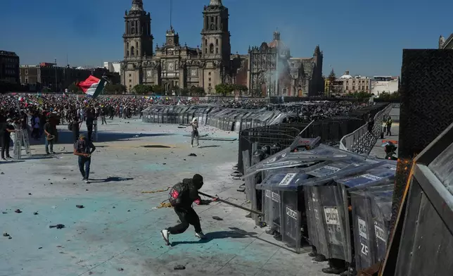 Protesters charge on police during a youth anti-government march in Mexico City, Saturday, Nov. 15, 2025. (AP Photo/Marco Ugarte)