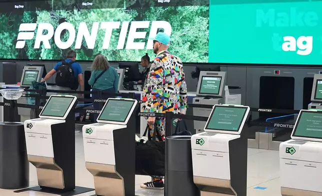 A traveller heads through a maze of empty kiosks to check in for a flight on Frontier Airlines in Denver International Airport Friday, Nov. 7, 2025, in Denver. (AP Photo/David Zalubowski)