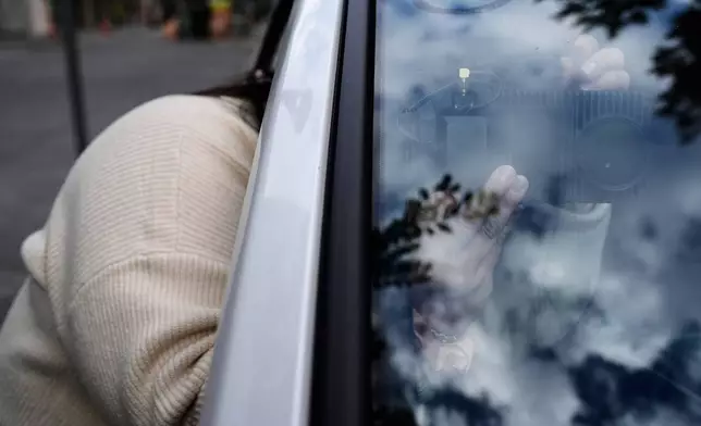 Chelsea Palacio, public information manager for the City of San Jose, adjusts a small detection camera – which uses AI to detect road hazards and potholes – mounted inside one of the city's parking enforcement vehicles, in San Jose, Calif., Wednesday, Nov. 12, 2025. (AP Photo/Godofredo A. Vásquez)