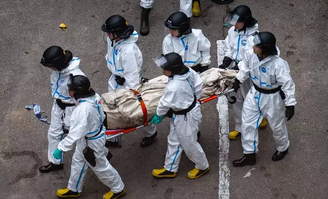 Police remove what appears to be a body bag from the site of a deadly Wednesday fire at Wang Fuk Court, a residential estate in the Tai Po district of Hong Kong's New Territories on Sunday, Nov. 30, 2025. (AP Photo/Chan Long Hei)