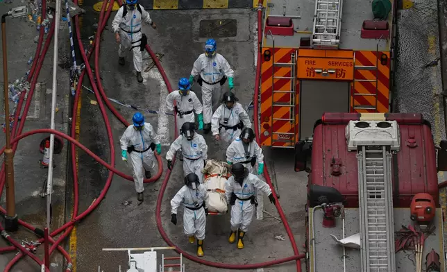 Emergency crew move what appears to be a body bag on a stretcher from the site of a deadly Wednesday fire at Wang Fuk Court, a residential estate in the Tai Po district of Hong Kong's New Territories on Sunday, Nov. 30, 2025. (AP Photo/Ng Han Guan)