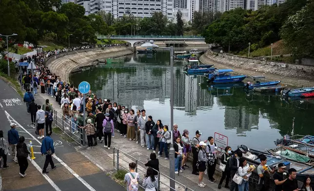 People line up to offer flowers and prayers for the victims near the site of a deadly Wednesday fire at Wang Fuk Court, a residential estate in the Tai Po district of Hong Kong's New Territories on Sunday, Nov. 30, 2025. (AP Photo/Chan Long Hei)