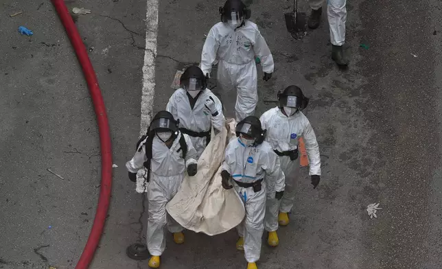 Police remove what appears to be a body bag from the site of a deadly Wednesday fire at Wang Fuk Court, a residential estate in the Tai Po district of Hong Kong's New Territories on Sunday, Nov. 30, 2025. (AP Photo/Ng Han Guan)