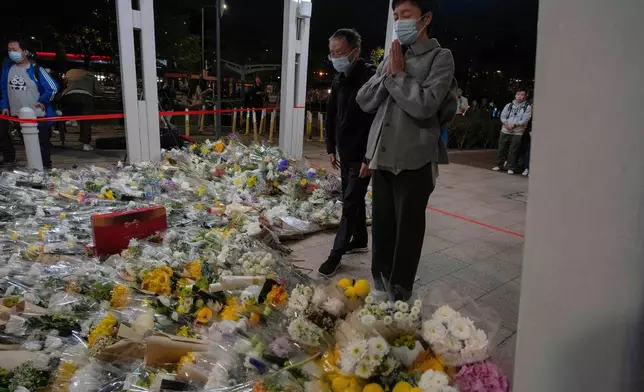 A woman prays after placing flowers near the site of the deadly Wednesday fire at Wang Fuk Court, a residential estate in the Tai Po district of Hong Kong's New Territories on Saturday, Nov. 29, 2025. (AP Photo/Ng Han Guan)