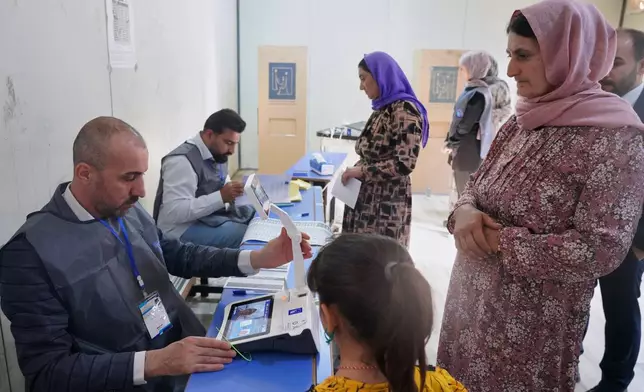 Displaced Yazidi women have their fingerprints verified before voting ahead of Iraq's parliamentary elections, set for Nov. 11, at a polling station in the Sharia camp near Dohuk, in Iraq's semi-autonomous Kurdish region, Sunday, Nov. 9, 2025. (AP Photo/Rashid Yahya)
