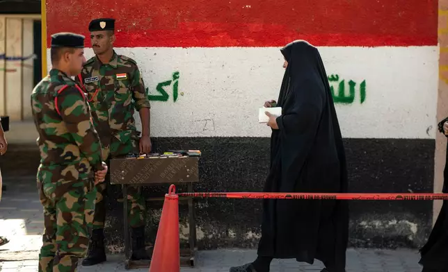 Iraqi police officers stand guard at a polling center as voters arrive to cast their ballots parliamentary elections in Najaf, Iraq, Tuesday, Nov. 11, 2025. (AP Photo/Anmar Khalil)