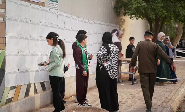 Voters search for their names before entering a polling station to vote during parliamentary elections in Kirkuk, northern Iraq, Tuesday, Nov. 11, 2025. (AP Photo/Sirwan Tahir)