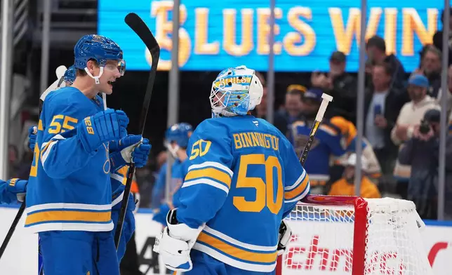 St. Louis Blues goaltender Jordan Binnington (50) and Colton Parayko (55) celebrate following an NHL hockey game against the Calgary Flames Tuesday, Nov. 11, 2025, in St. Louis. (AP Photo/Jeff Roberson)
