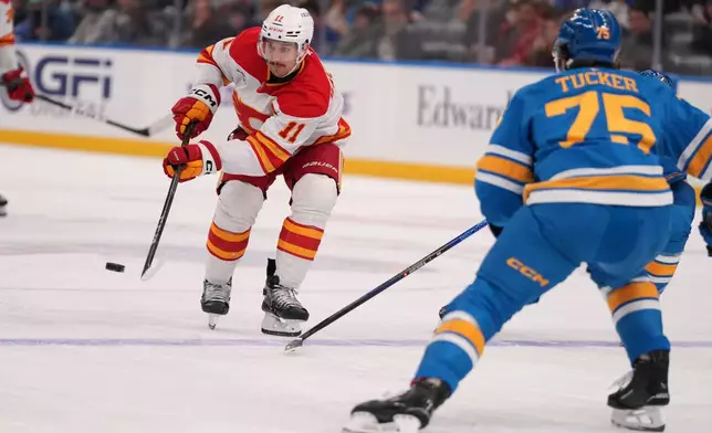 Calgary Flames' Mikael Backlund (11) passes as St. Louis Blues' Tyler Tucker (75) defends during the third period of an NHL hockey game Tuesday, Nov. 11, 2025, in St. Louis. (AP Photo/Jeff Roberson)