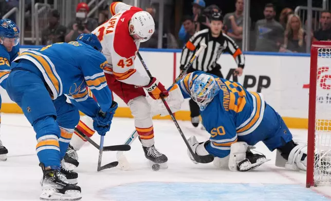 Calgary Flames' Adam Klapka (43) is unable to score past St. Louis Blues goaltender Jordan Binnington (50) and Philip Broberg, left, during the third period of an NHL hockey game Tuesday, Nov. 11, 2025, in St. Louis. (AP Photo/Jeff Roberson)