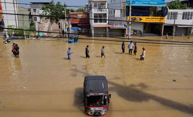 Flood victims wade through a submerged area of Colombo, Sri Lanka, on Sunday, Nov. 30, 2025. (AP Photo/Eranga Jayawardena)