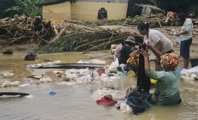 People use flood water to remove mud from clothings at a village hit by a flash flood in Batang Toru, North Sumatra, Indonesia, Saturday, Nov. 29, 2025. (AP Photo)