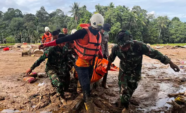 Rescuers carry the body of a flood victim, in Agam, West Sumatra, Indonesia, Sunday, Nov. 30, 2025. (AP Photo/Ade Yuandha)