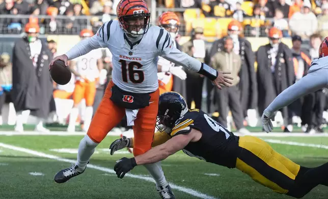 Cincinnati Bengals quarterback Joe Flacco (16) avoids a tackle by Pittsburgh Steelers linebacker T.J. Watt (90) during the first half of an NFL football game Sunday, Nov. 16, 2025, in Pittsburgh. (AP Photo/Gene J. Puskar)