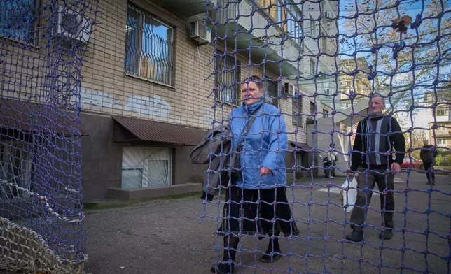 Local residents go along the street covered with an anti-FPV-drone net in the frontline city of Kherson, Southern Ukraine, Nov. 3, 2025. (AP Photo/Efrem Lukatsky)