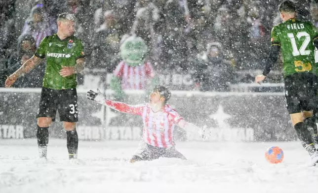 Atletico Ottawa's David Rodríguez, center, sits in the snow as he reacts to a call by a referee (not shown) during second-half Canadian Premier League finals soccer match action against Cavalry FC in Ottawa, Ontario, Sunday, Nov. 9, 2025. (Spencer Colby/The Canadian Press via AP) I