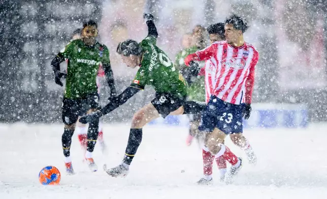 Cavalry FC's Tobias Warschewski (9) losses his footing as he attempts to gain possession of the ball from Atletico Ottawa's Noah Abatneh (23) during first half Canadian Premier League finals soccer action in Ottawa, on Sunday, Nov. 9, 2025. (Spencer Colby/The Canadian Press via AP)