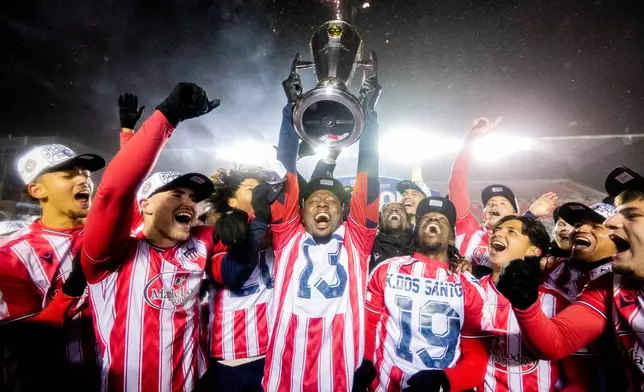 Atletico Ottawa's Ballou Tabla (13) raises the North Star Cup following Atletico Ottawa's victory over Cavalry FC in extra time during the Canadian Premier League finals soccer action in Ottawa, on Sunday, Nov. 9, 2025. (Spencer Colby/The Canadian Press via AP)