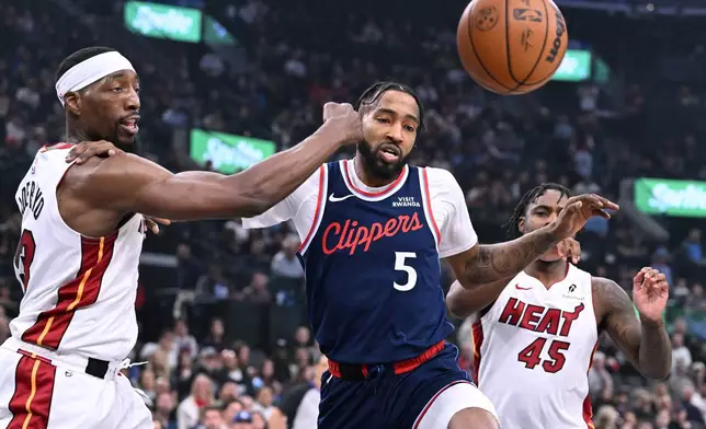 Miami Heat forward Bam Adebayo, left, and teammate Davion Mitchell (45) battle for the ball with Los Angeles Clippers forward Derrick Jones Jr. (5) during the first half of an NBA basketball game Monday, Nov. 3, 2025, in Los Angeles. (AP Photo/Wally Skalij)