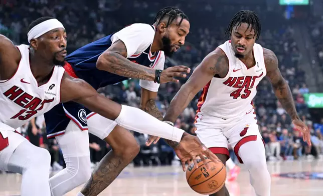 Miami Heat forward Bam Adebayo (13) and teammate Davion Mitchell (45) battle for the ball with Los Angeles Clippers forward Derrick Jones Jr., center, during the first half of an NBA basketball game Monday, Nov. 3, 2025, in Los Angeles. (AP Photo/Wally Skalij)