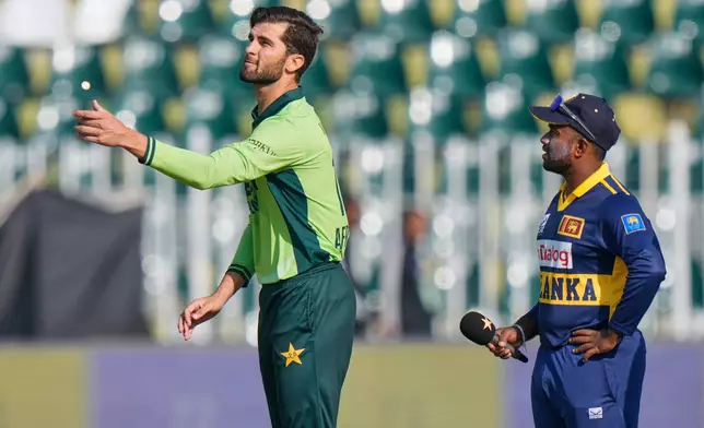 Pakistan's Shaheen Shah Afridi, left, flips the coin for toss as Sri Lanka's Charith Asalanka watches before start of the first one day international cricket match between Pakistan and Sri Lanka, in Rawalpindi, Pakistan, Tuesday, Nov. 11, 2025. (AP Photo/Anjum Naveed)