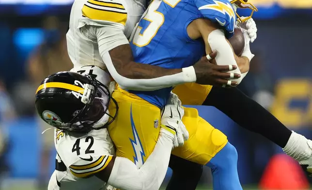 Los Angeles Chargers wide receiver Ladd McConkey (15) is taken down by Pittsburgh Steelers cornerback James Pierre (42) and cornerback Jalen Ramsey (5) during the second half of an NFL football game Sunday, Nov. 9, 2025, in Inglewood, Calif. (AP Photo/Jessie Alcheh)