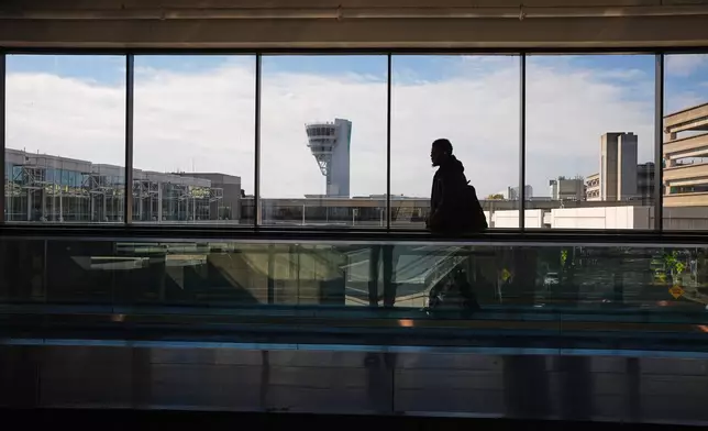 A traveler moves in view of a control tower at Philadelphia International Airport in Philadelphia, Wednesday, Nov. 5, 2025. (AP Photo/Matt Rourke)