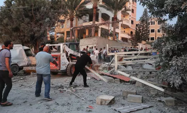 People inspect the site of a building destroyed by an Israeli airstrike in the village of Teir Debba, southern Lebanon, Thursday, Nov. 6, 2025. (AP Photo/Mohammad Zaatari)