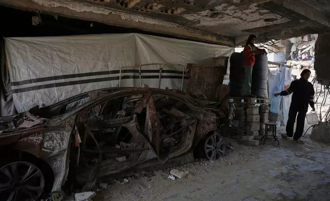 Taj al-Hindi, 14, and her sister, Rimas al-Hindi, 15, fill water tanks inside a school that was bombed in July 2024 in Khan Younis during the Israel-Hamas war, Wednesday, Nov. 12, 2025. (AP Photo/Abdel Kareem Hana)