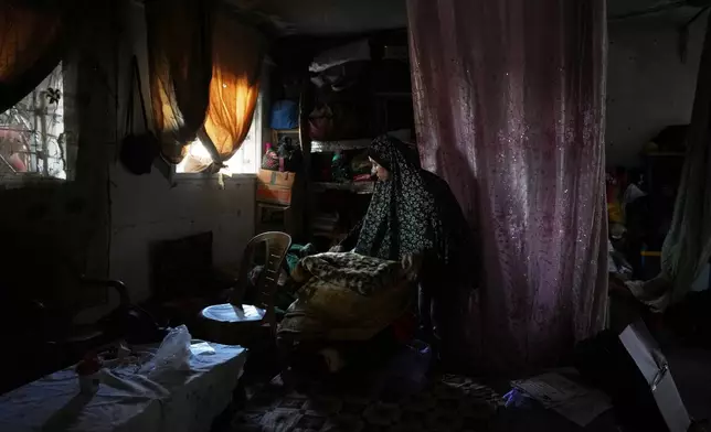 Tahreer al-Awaini arranges blankets inside a classroom at a school that was bombed in July 2024 in Khan Younis during the Israel-Hamas war, Wednesday, Nov. 12, 2025. (AP Photo/Abdel Kareem Hana)