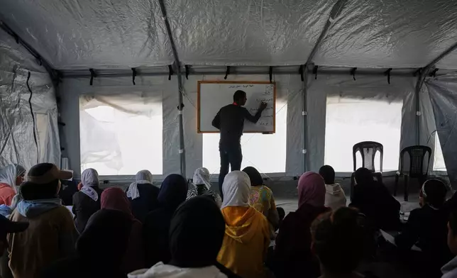 Palestinian students attend class inside a tent set up on the beach in Khan Younis, Gaza Strip, Wednesday, Nov. 12, 2025. (AP Photo/Abdel Kareem Hana)