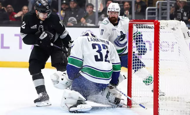Vancouver Canucks goaltender Kevin Lankinen (32) makes a save against Los Angeles Kings left wing Trevor Moore (12) as Vancouver Canucks defenseman Filip Hronek (17) watches during the second period of an NHL hockey game, Saturday, Nov. 29, 2025, in Los Angeles. (AP Photo/Jessie Alcheh)