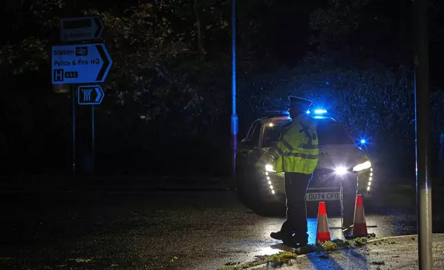 Police stand guard near the Huntingdon, England, train station in Cambridgeshire, after people were stabbed on a train, Saturday, Nov. 1, 2025. (Chris Radburn/PA via AP)