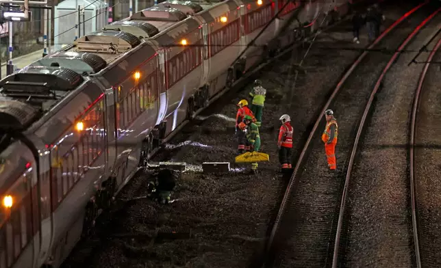Emergency personnel inspect a train at the Huntingdon, England, train station in Cambridgeshire after people were stabbed Saturday, Nov. 1, 2025. (Chris Radburn/PA via AP)