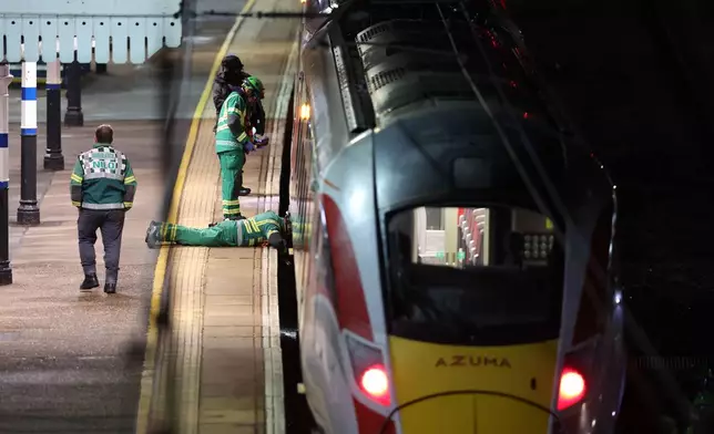 Emergency personnel inspect a train at the Huntingdon, England, train station in Cambridgeshire after people were stabbed Saturday, Nov. 1, 2025. (Chris Radburn/PA via AP)