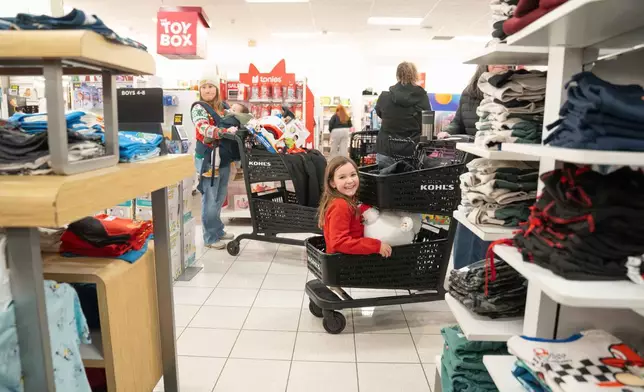 Eva Klein sits in the bottom of her grandmothers shopping cart as shoppers browse through Kohl's department store for Black Friday, Friday, Nov. 28, 2025, in Woodstock, Ga. (AP Photo/Megan Varner)